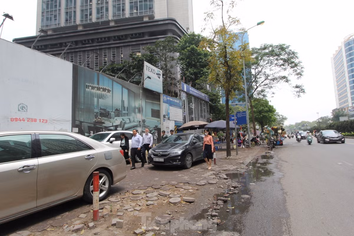 Nhiều dự án chung cư trên đường Lê Văn Lương (quận Thanh Xuân) tự ý san hạ cốt nền vỉa hè để làm lối đi riêng cho ô tô và xe máy vào tòa nhà. (Ảnh: Lập Đông)
