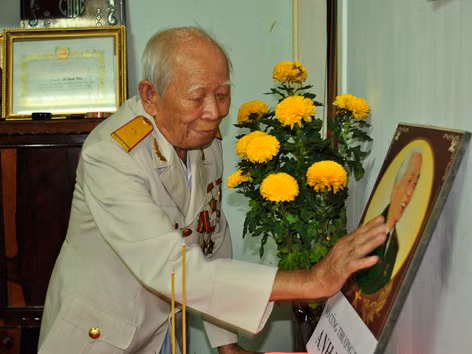 Cụ Cắm vuốt nhẹ di ảnh Đại tướng trên bàn thờ