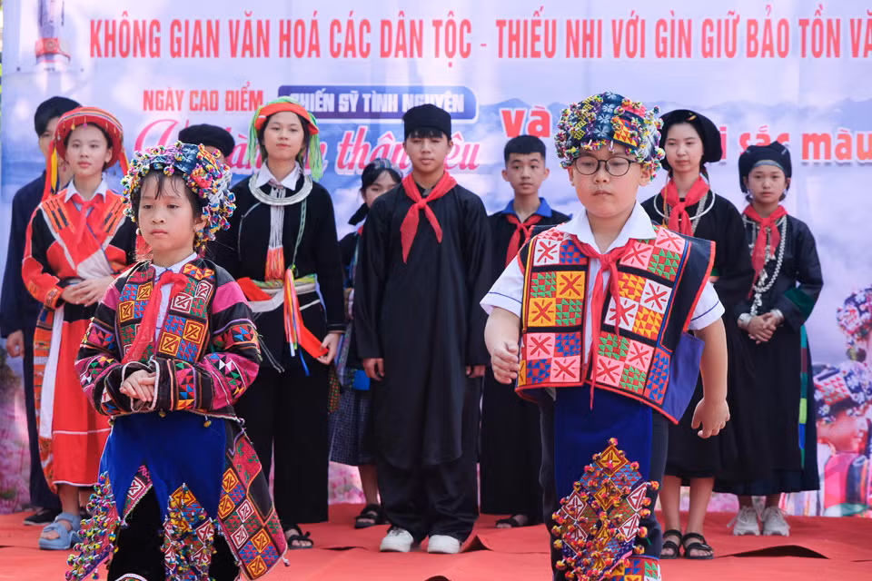 Trang phục dân tộc Lô Lô do 2 em đến từ Hội đồng Đội huyện Mèo Vạc trình diễn. Người Lô Lô ở đây phân chia thành hai nhánh là Lô Lô Đen và Lô Lô Hoa, chủ yếu sinh sống tại các xã của Huyện Đồng Văn, Mèo Vạc và chỉ có sự khác nhau về trang phục truyền thống. Trang phục của người Lô Lô Đen có áo cổ vuông, xẻ ngực cài khuy bằng vải hoặc đồng. Ống tay áo được trang trí nhiều họa tiết hoa văn hoặc đính kèm nhiều miếng vải màu khác nhau. Sống lưng áo trang trí các họa tiết hình vuông nhỏ. Còn trang phục của dân tộc Lô Lô Hoa mặc áo cổ tròn, màu đen hoặc chàm, xẻ ngực. Toàn bộ áo được thêu đính kèm những miếng vải với các màu sắc đỏ, xanh, vàng, trắng. Váy là một điểm nhấn trong bộ trang phục truyền thống của người Lô Lô Đen, chia làm ba lớp: lớp ngoài cùng là những dải tua rua gắn với chùm bông len đủ màu sắc; lớp thứ hai là tấm vải quấn váy chắp nhiều mảng hoa văn; lớp trong cùng là chiếc váy xòe xếp ly màu đen. Hoa văn phổ biến trên vải quấn váy là hoa văn pá pú.