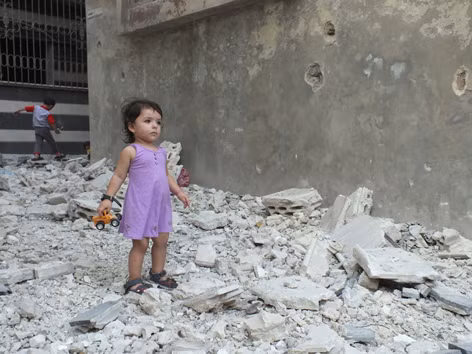 Hai em bé Syria chơi trên nền ngôi nhà bị đánh sập vì giao tranh giữa quân chính phủ và phe nổi dậy ở thành phố Homs. Ảnh: Latitude News
