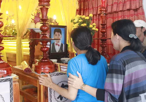 Chị Huỳnh Thị Thanh Thảo (mặc áo xanh), vợ anh Lộc và mẹ bé Tài, khóc nức nở bên ảnh và quan tài chồng, con