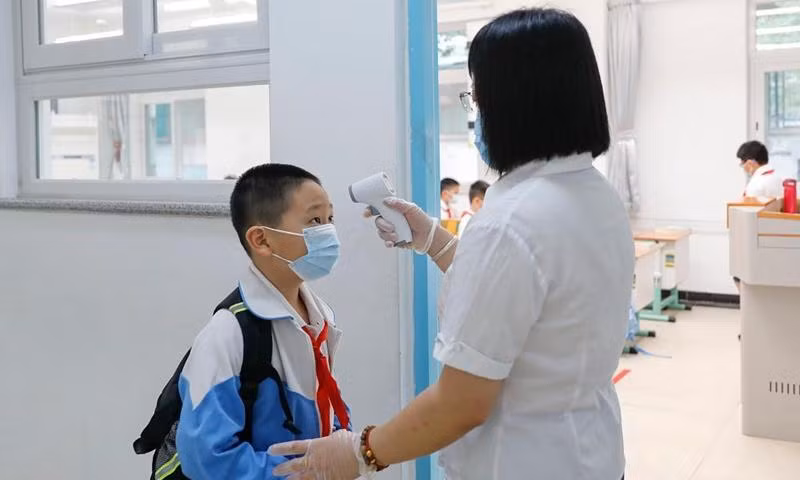 Một học sinh ở Bắc Kinh (Trung Quốc) được đo thân nhiệt trước khi vào lớp. Ảnh: Global Times