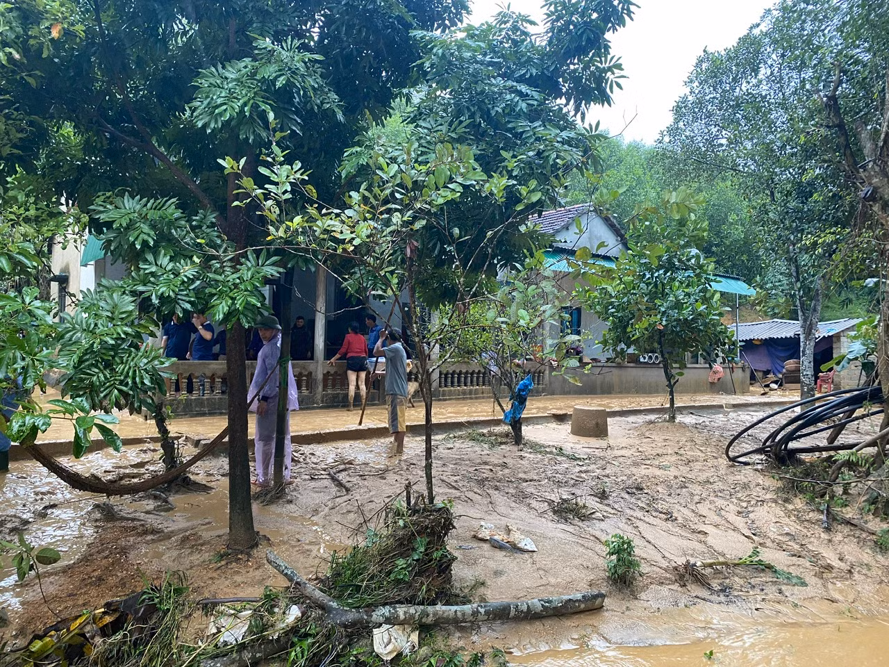 Ngành chức năng phối hợp với người dân địa phương đến hỗ trợ gia đình bị lũ ống dọn dẹp nhà cửa.