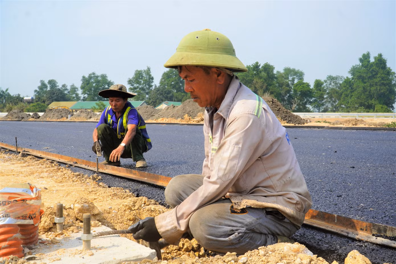 Những thảm lớp bê tông nhựa cuối cùng đang được công nhân hoàn thiện.