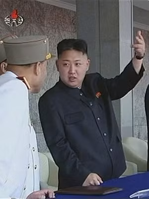 Nhà lãnh đạo Kim Jong-un giơ tay khi đoàn diễu binh đi qua Ảnh: CCTV