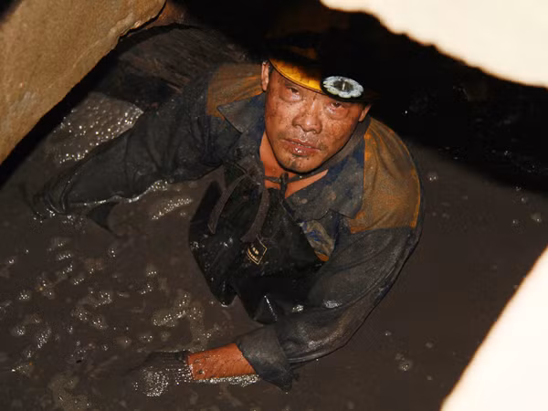 Bùn dưới cống ngập ngang ngực công nhân thoát nước Ảnh: Trường Phong