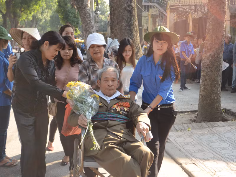 Người thương binh phải ngồi xe lăn nhưng vẫn muốn đến viếng Đại tướng với bó hoa Cúc vàng