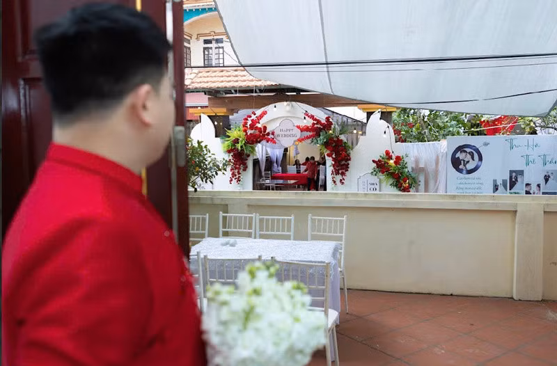 Chú rể đứng trước cửa nhà ngó sang cổng cưới nhà cô dâu.