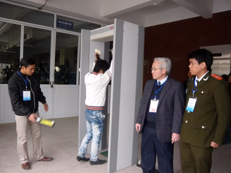 Ông Phan Văn Minh-Giám đốc Trung tâm lao động ngoài nước và cán bộ Phòng A83 Công an Hà Nội chỉ đạo kiểm tra thí sinh dùng điện thoại tại các cổng từ