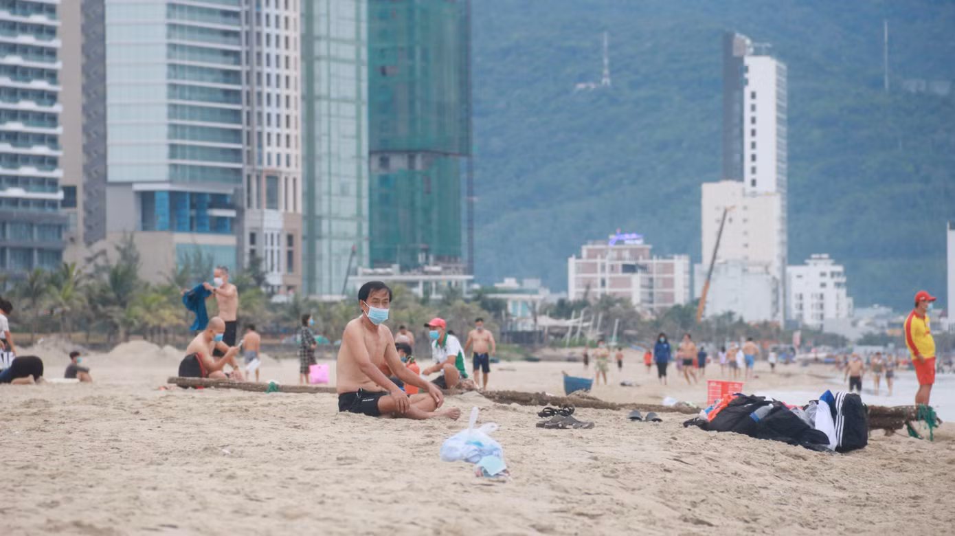 Một người dân đeo khẩu trang ngồi hít thở không khí trong lành trên bãi biển Đà Nẵng.
