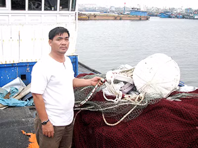 Ngư dân Trương Văn Hai với con tàu từng trầy trật vì bảo hiểm Ảnh: Nam Cường