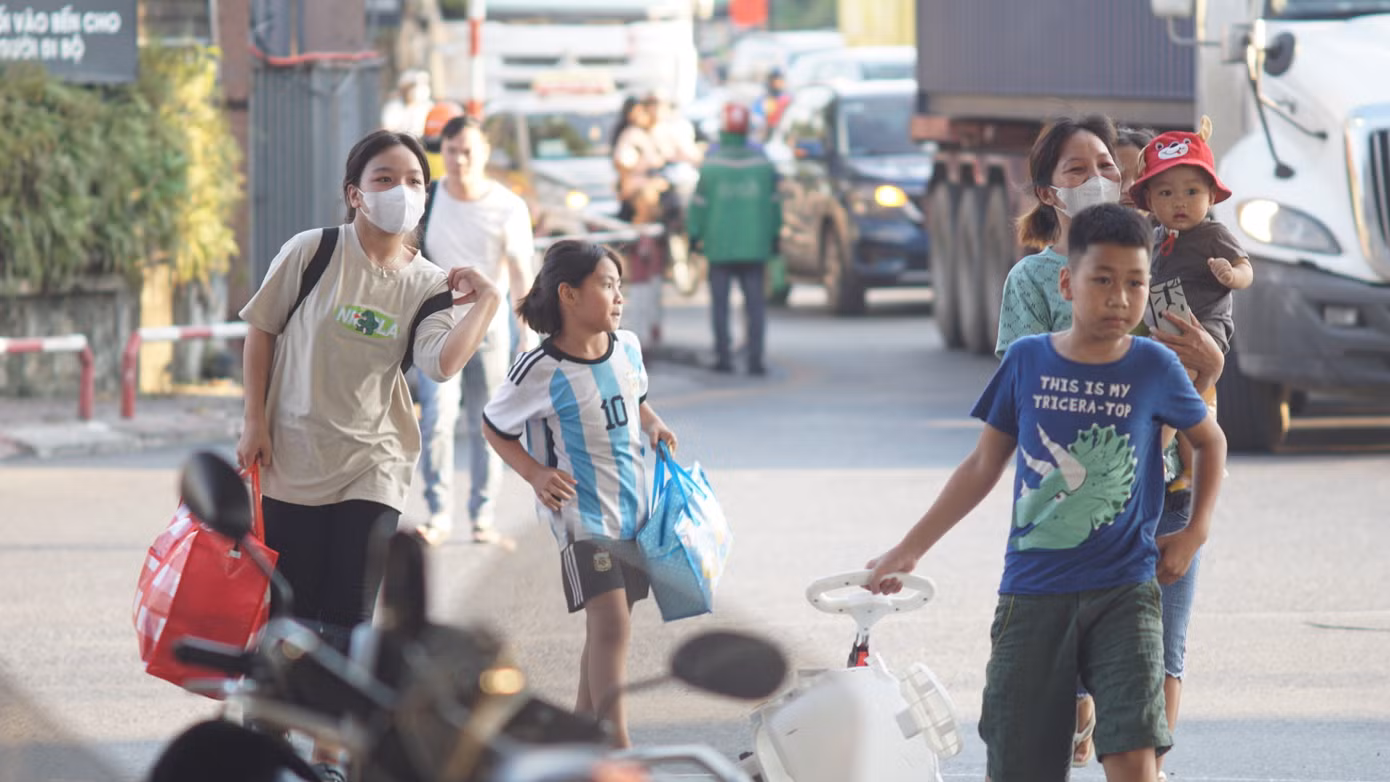 Nhiều gia đình có con nhỏ lỉnh kỉnh đồ đạc di chuyển trên đường.