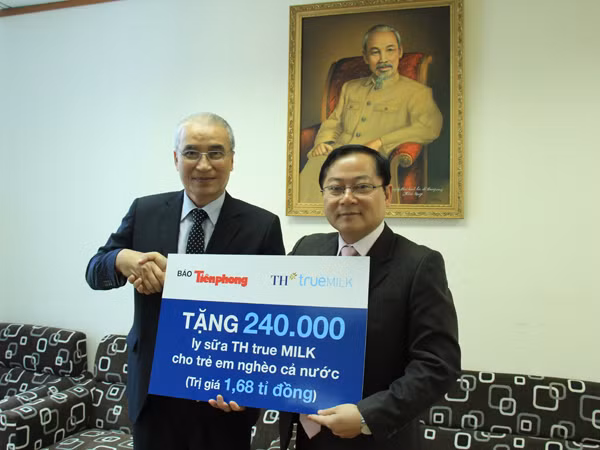 Phó Tổng Giám đốc Tập đoàn TH Ngô Minh Hải (bìa trái) trao tượng trưng sữa từ thiện cho Tổng Biên tập Lê Xuân Sơn. Ảnh: Trường Phong