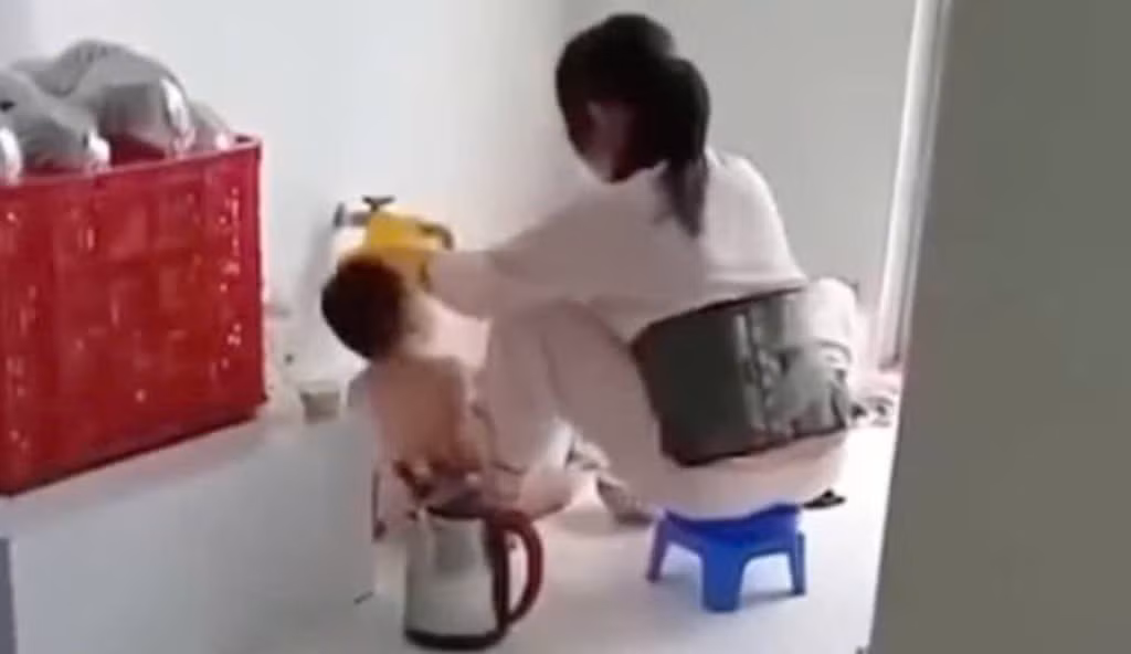 Nhân viên nấu ăn nhóm mầm non Thu Sương (Ba Tri, Bến Tre) nhồi nhét thức ăn vào miệng trẻ em. Ảnh cắt từ clip.