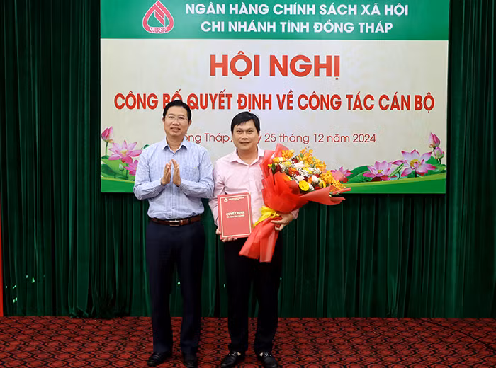 Phó Chủ tịch UBND tỉnh Đồng Tháp - Huỳnh Minh Tuấn (trái) trao quyết định và hoa chúc mừng ông Trần Đăng Nhiên. Ảnh: V. Tiến.