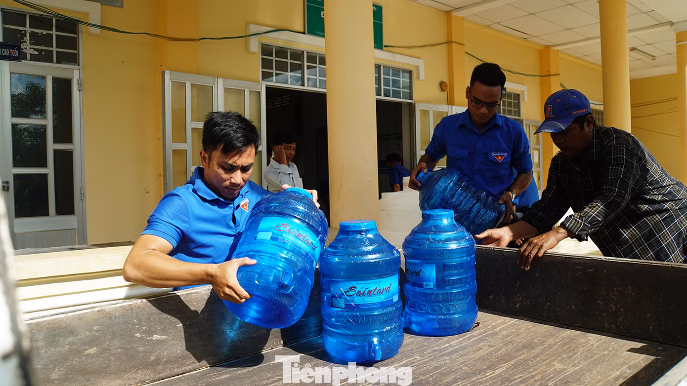 Đoàn viên thanh niên xã Long Phú mang nước lên xe chở đến tận nhà giúp người dân. Ảnh: Hòa Hội