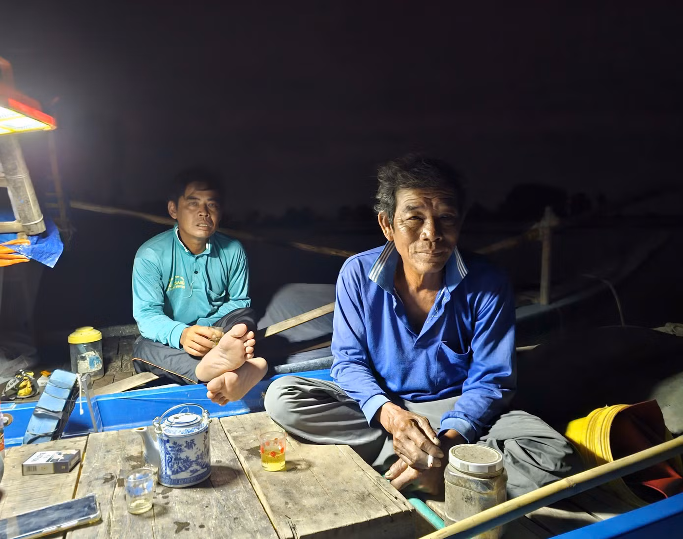 Hơn 2h sáng, ngày cuối tháng 10, ông Lê Văn Thảo (trái) ở xã Phú Hiệp, huyện Phú Tân, (An Giang) thức dậy chuẩn bị ra cánh đồng biên giới giăng lưới, thả câu. Ông Thảo cùng nhóm bạn giăng lưới, thả câu với 6 chiếc xuồng cặp nhau, cả nhóm thức dậy đốt lửa pha ấm trà, bàn chuyện cá mắm. Ảnh: Hòa Hội. Hơn 2h sáng, ngày cuối tháng 10, ông Lê Văn Thảo (trái) ở xã Phú Hiệp, huyện Phú Tân, (An Giang) thức dậy chuẩn bị ra cánh đồng biên giới giăng lưới, thả câu. Ông Thảo cùng nhóm bạn giăng lưới, thả câu với 6 chiếc xuồng cặp nhau, cả nhóm thức dậy đốt lửa pha ấm trà, bàn chuyện cá mắm. Ảnh: Hòa Hội.