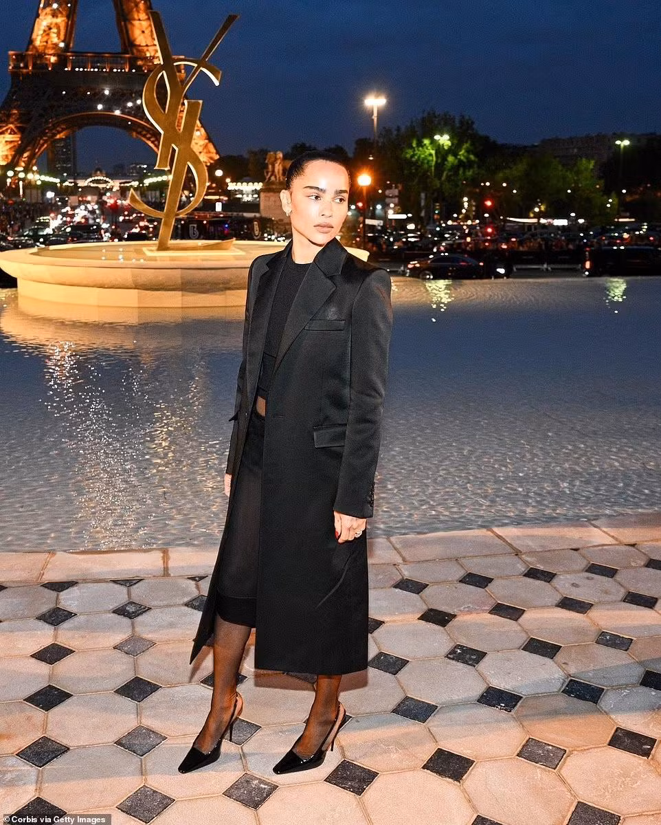 Miêu nữ Zoe Kravitz phối áo crop top với chân váy xuyên thấu, áo khoác nỉ dáng dài và giày cao gót đen trông khá nghiêm túc.
