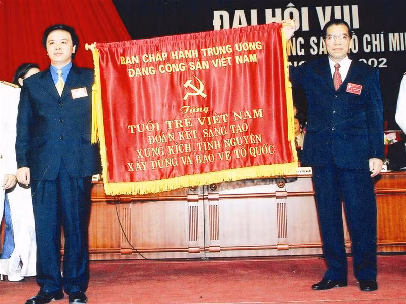 Đồng chí Hoàng Bình Quân (trái) nhận cờ của BCH T.Ư Đảng tại Đại hội Đoàn toàn quốc lần thứ VIII (2002)