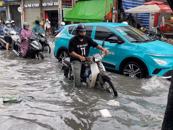Người dân vất vả lưu thông qua tuyến đường ngập.