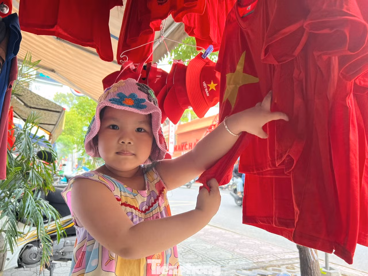 Một em bé vui thích được mẹ mua cho áo mới có hình sao vàng để mặc xem đại lễ Một em bé vui thích được mẹ mua cho áo mới có hình sao vàng để mặc xem đại lễ