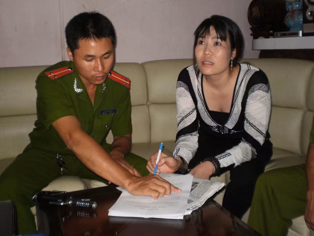 Nguyễn Thị Trâm, bị còng tay phải ký vào biên bản xử lý.