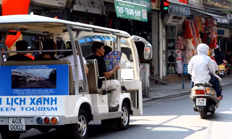 Khách du lịch ngồi trên xe điện vẫn không ngơi tay quạt mạt để xua hơi nóng