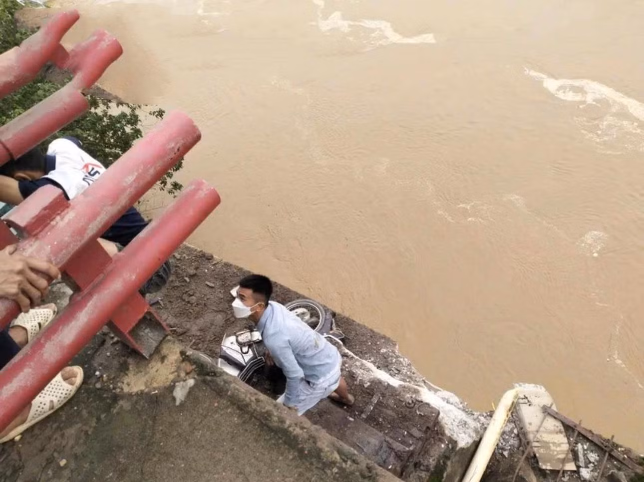 Thời điểm sập cầu, một nam thanh niên may mắn rơi xuống mô đất đoạn nước chưa dâng lên. (Ảnh: Giang Như Nguyễn)