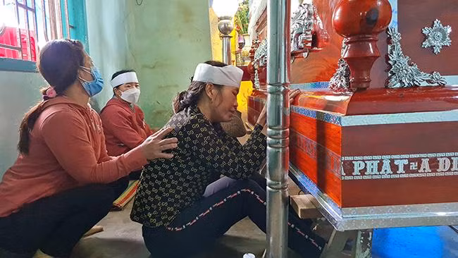 Mẹ của Ng., người ngồi gần quan tài đeo khăn tang khóc thương con. (Ảnh: Lâm Thiên)