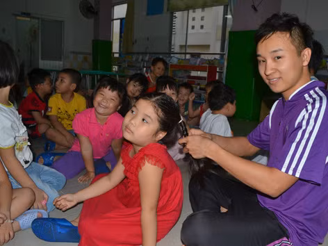 Thầy Nguyễn Hữu Toàn đang buộc tóc cho một bé trong lớp