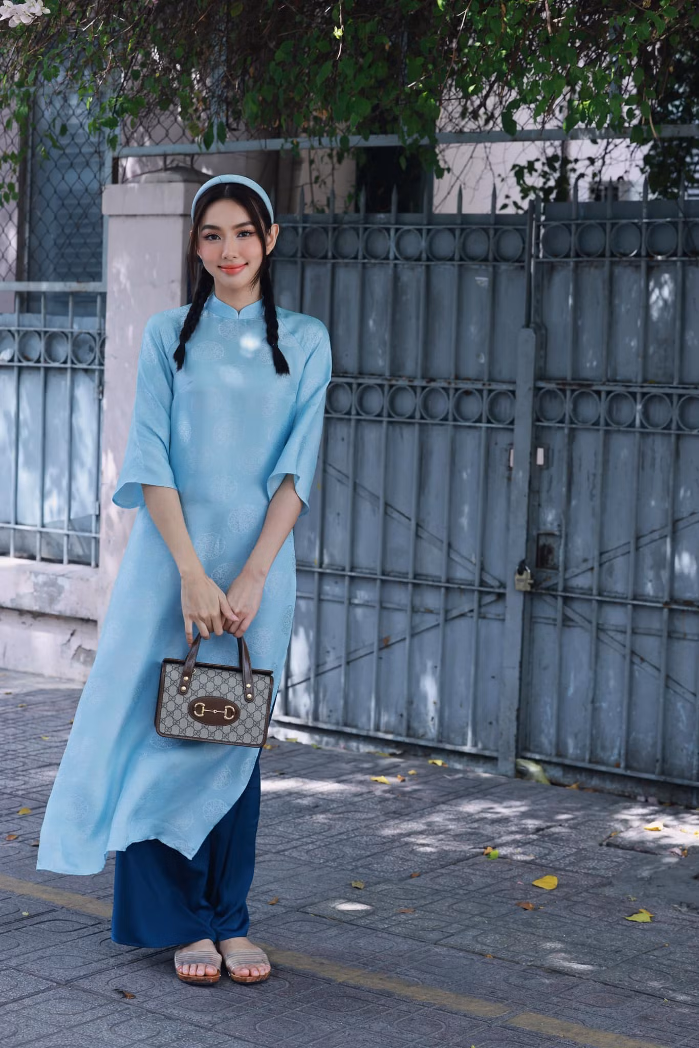 Nàng hậu chọn kiểu tóc tết năng động, diện áo dài với túi xách cỡ trung.