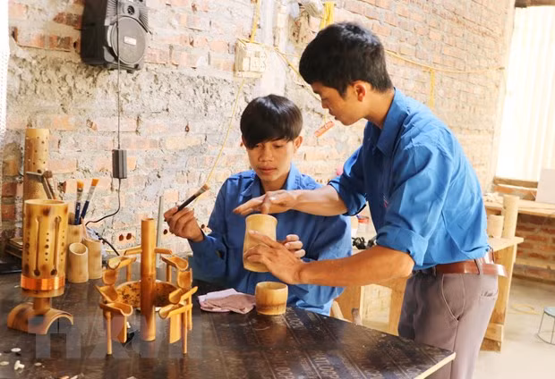 Anh Hà Văn Thời hướng dẫn các thanh niên sơn bóng cho sản phẩm. (Ảnh: Đinh Thùy/TTXVN)