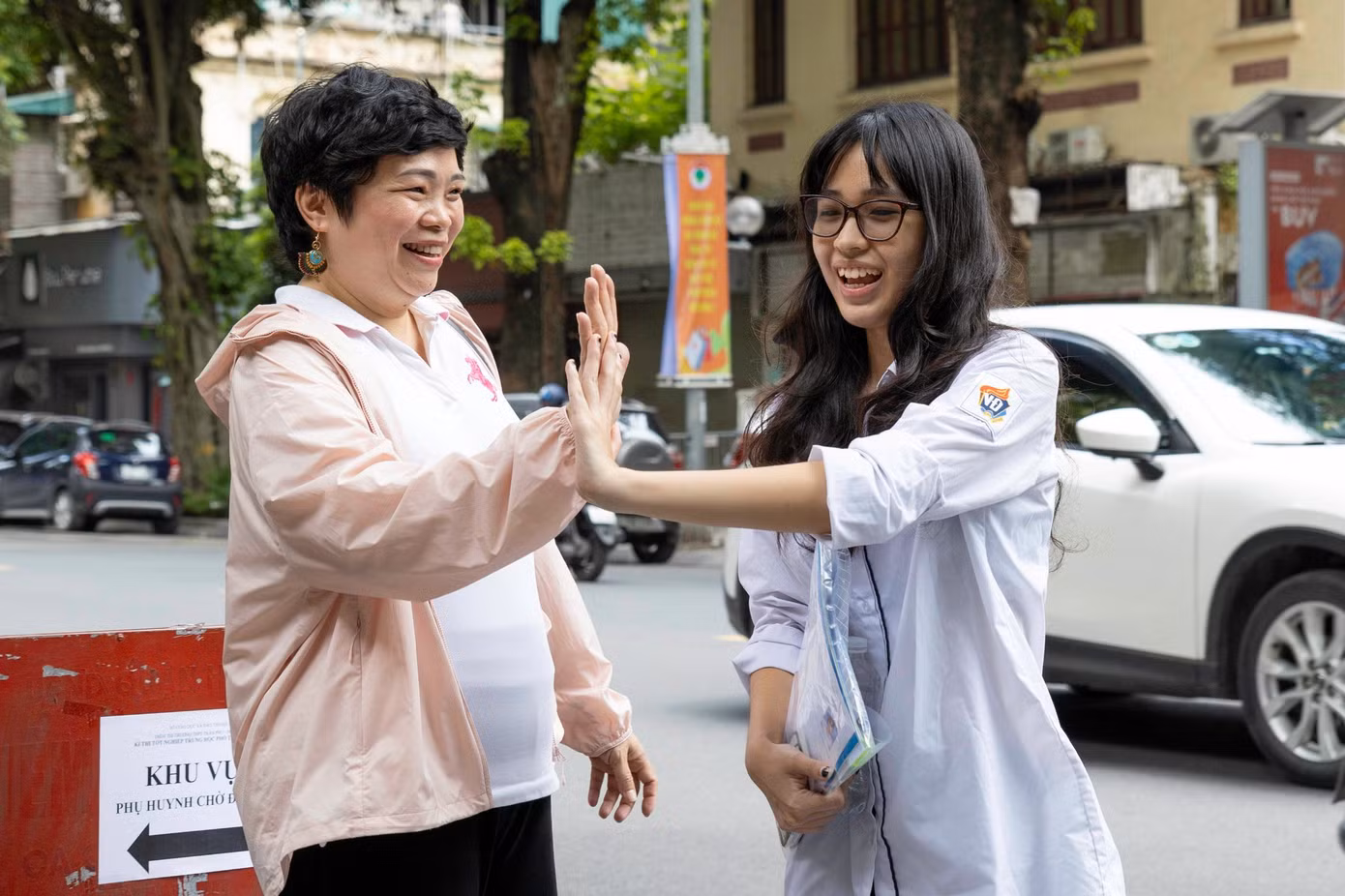 Cô Phan Hồng Giang đập tay chúc mừng con gái sau bài thi tổ hợp. Cô Giang chia sẻ: "Thấy con và các bạn ra khỏi phòng thi đều rất là vui vẻ và tự tin, cô rất vui. Bạn nhà cô có mong muốn thi vào Trường Đại học Khoa học Xã hội &amp; Nhân văn, bạn ấy đã rất kiên trì, bền bỉ và nỗ lực trong quá trình học tập. Cô luôn đồng hành cùng bạn với vai trò là một người bạn, một người cố vấn để cho bạn có thể tìm hiểu về ngành nghề, môn học, nếu các bạn ý cần sự hỗ trợ nào thì mình có thể kết nối với các thầy cô để hỗ trợ và tư vấn." (Ghi nhận tại điểm thi Trường THPT Trần Phú - Hà Nội)