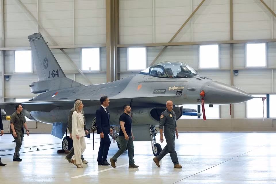 Hai quan chức đi bên cạnh một chiếc F-16. Ảnh: Reuters Hai quan chức đi bên cạnh một chiếc F-16. Ảnh: Reuters