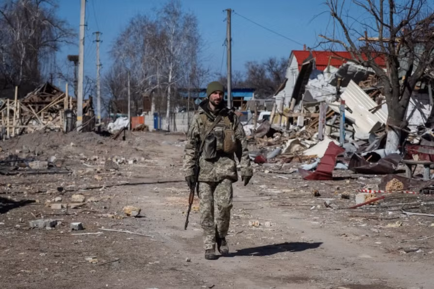 Lính Ukraine đi trong một ngôi làng đổ nát ở ngoại ô thủ đô Kiev ngày 21/3 Ảnh: Reuters Lính Ukraine đi trong một ngôi làng đổ nát ở ngoại ô thủ đô Kiev ngày 21/3 Ảnh: Reuters