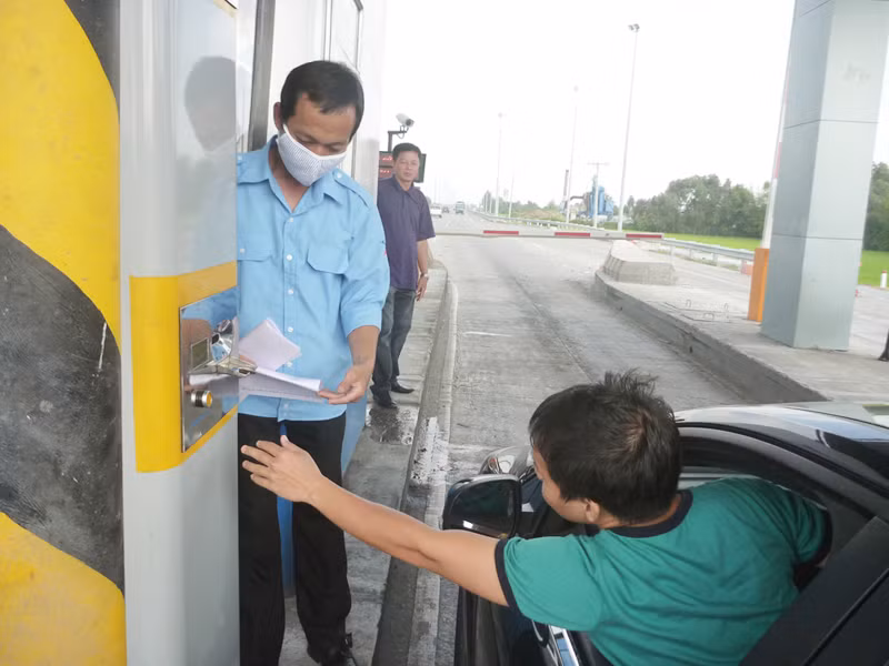 Lái xe bấm vào máy để nhận thẻ tại trạm thu phí Thân Cửu Nghĩa. Ảnh: Đức Thịnh