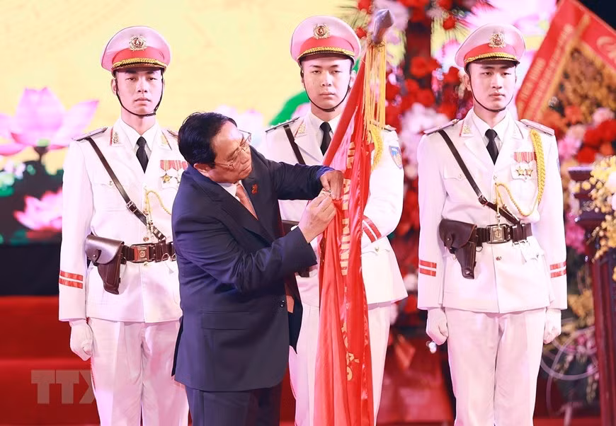 Thủ tướng Phạm Minh Chính gắn Huân chương Bảo vệ Tổ quốc hạng Nhất lên Cờ truyền thống của lực lượng An ninh Kinh tế. (Ảnh: Dương Giang/TTXVN)