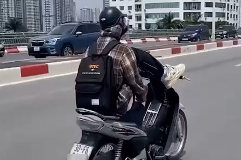 Hình ảnh nam thanh niên dùng chân lái xe máy. Ảnh chụp màn hình
