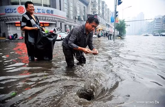Hai người đàn ông tại một miệng cống thoát nước trên một đường phố ở Thẩm Dương, thủ phủ tỉnh Liêu Ninh, đông bắc Trung Quốc, ngày 16/8/2013. Ảnh: Tân Hoa Xã 