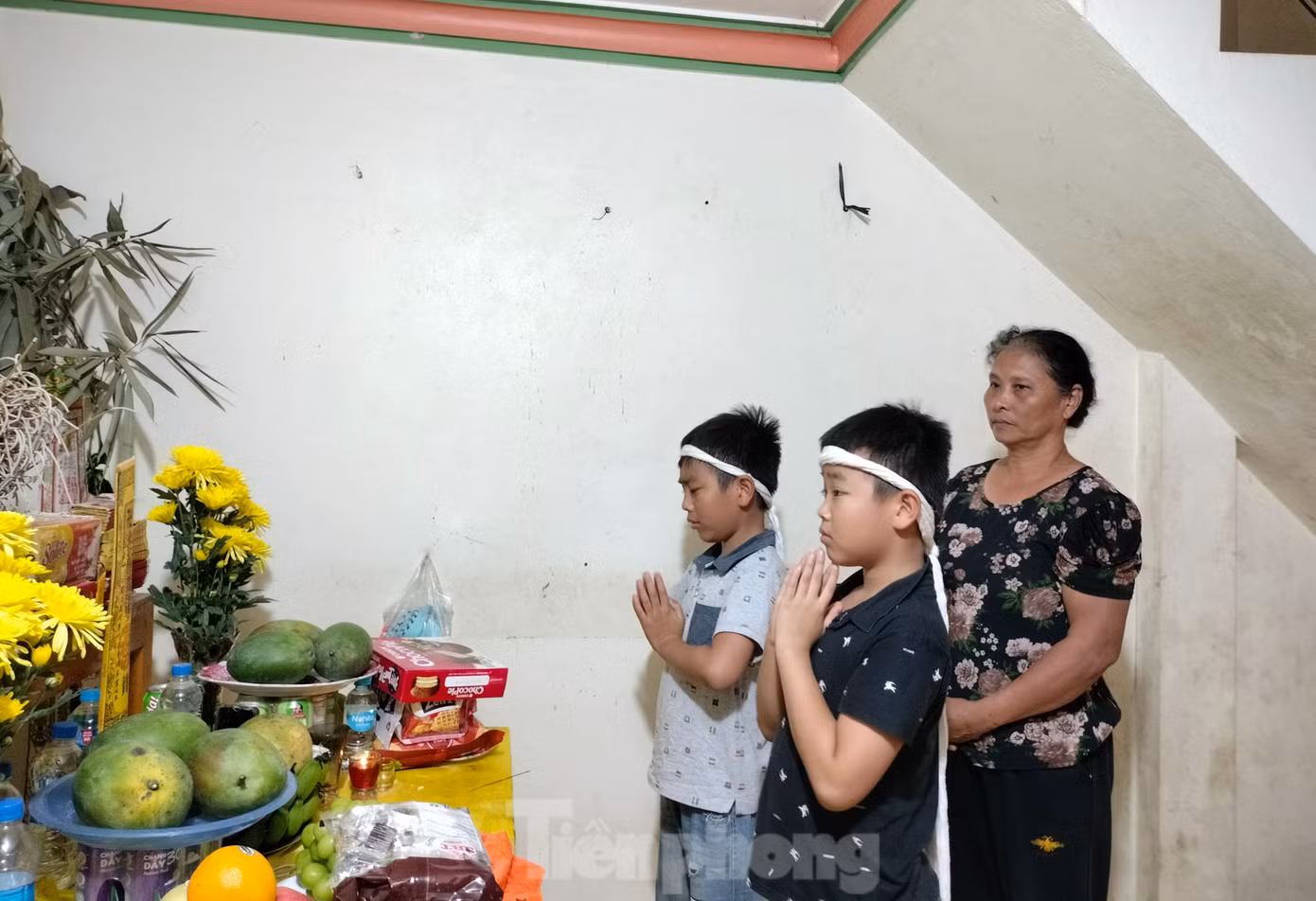 Cháu Bảo (áo đen) cùng cháu Việt (áo xanh nhạt) thắp hương cho bố mẹ.