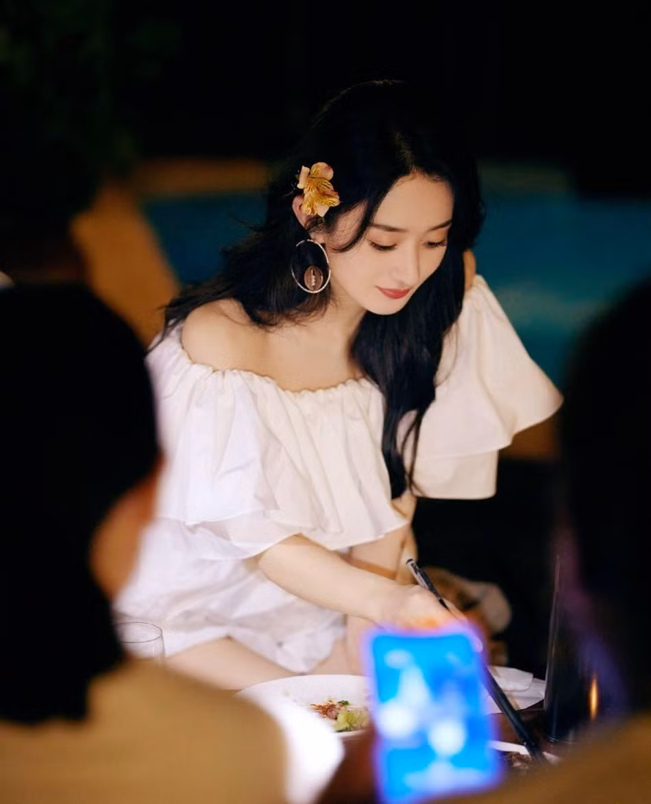 Triệu Lệ Dĩnh mặc một chiếc váy ngắn lệch vai màu trắng với mái tóc dài uốn xoăn nhẹ, tươi tắn và xinh đẹp.