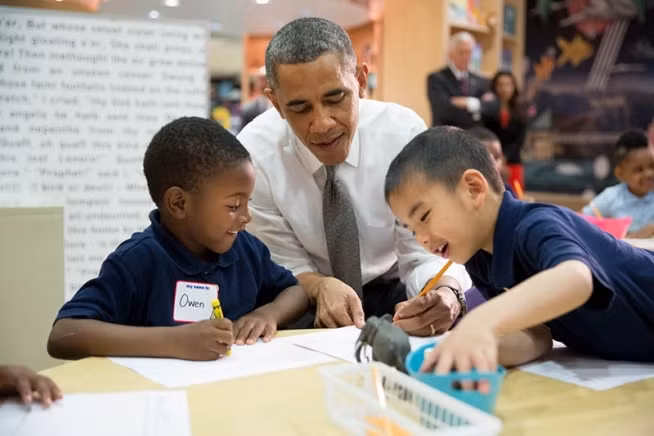 Tổng thống Obama ngồi viết cùng các em nhỏ ở trường tiêu học Moravia, Baltimore hôm 17/5/2013