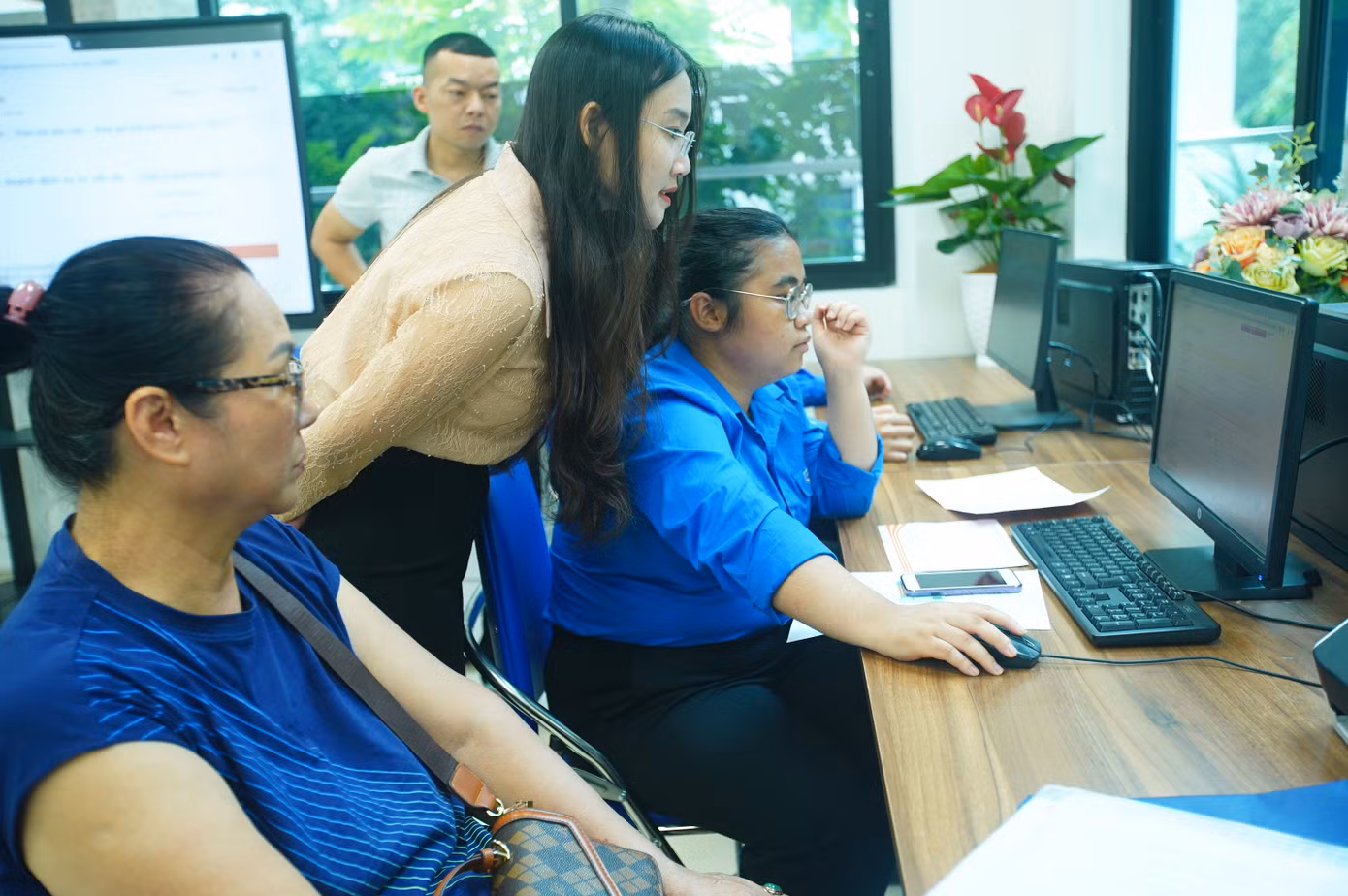 Tình nguyện viên "trực chiến" bên khu vực máy tính, giúp người dân kê khai online, nhập dữ liệu nhanh chóng.