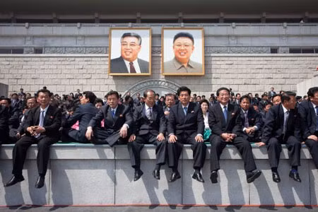 Người xem diễu binh dưới hai bức chân dung lớn của các nhà lãnh đạo Kim Nhật Thành và Kim Jong-il. 