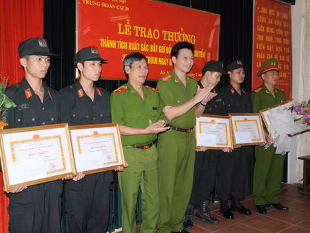 Thiếu tướng Trần Thùy - Phó Giám đố CATP Hà Nội (thứ ba, từ trái qua) trao thưởng cho các cán bộ, chiến sĩ trong Đại đội 12 đã xuất sắc bắt giữ hai đối tượng, thu 26 bánh heroin