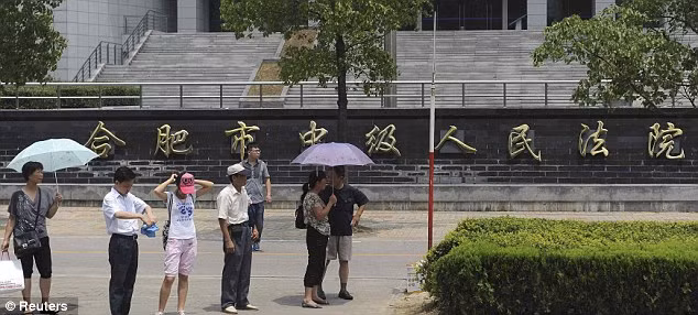 Những người đi đường đứng lại ở bên ngoài tòa án nhân dân thành phố Hợp Phì, tỉnh An Huy, nơi sẽ diễn ra phiên tòa xét xử bà Cốc Khai Lai