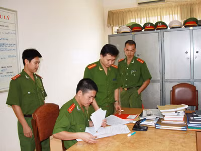 Thượng úy Bùi Việt Hùng (ngoài cùng bìa trái) cùng đồng đội nghiên cứu hồ sơ các vụ án Ảnh: Trường Phong