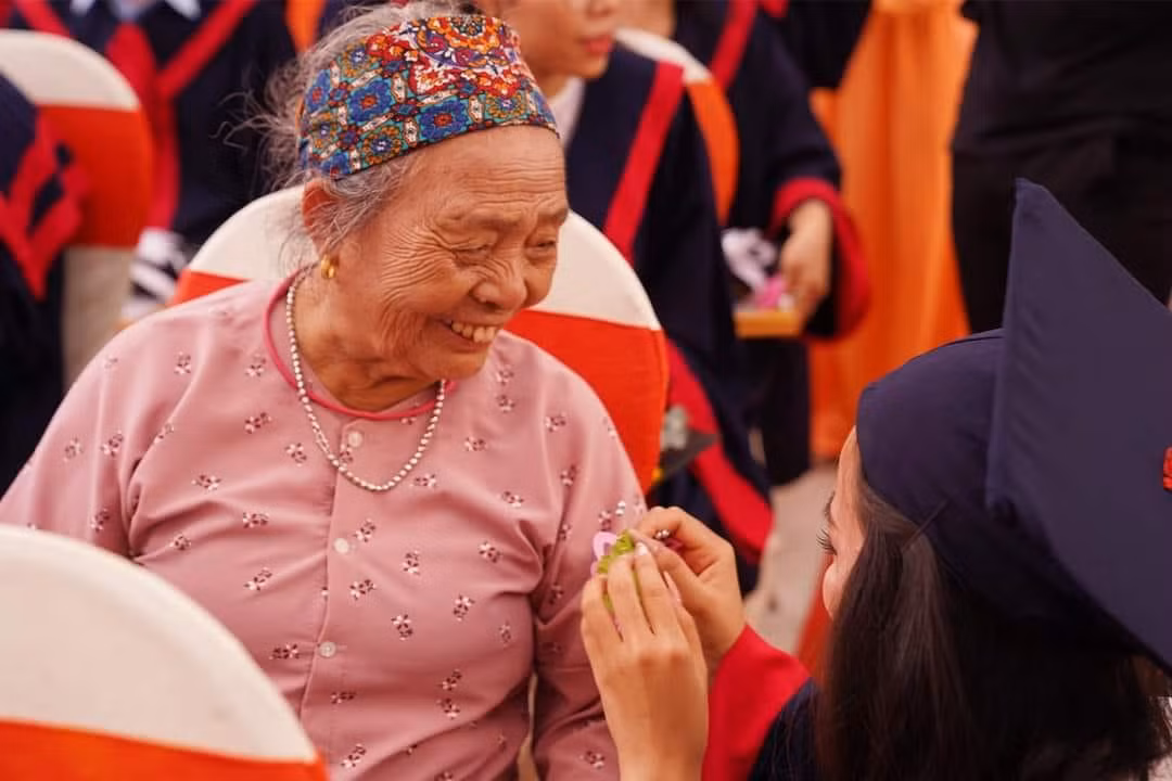 Tâm gắn hoa lên áo bà thể hiện lòng biết ơn của mình. (Ảnh: Trường ĐH Công nghệ Miền Đông) Tâm gắn hoa lên áo bà thể hiện lòng biết ơn của mình. (Ảnh: Trường ĐH Công nghệ Miền Đông)