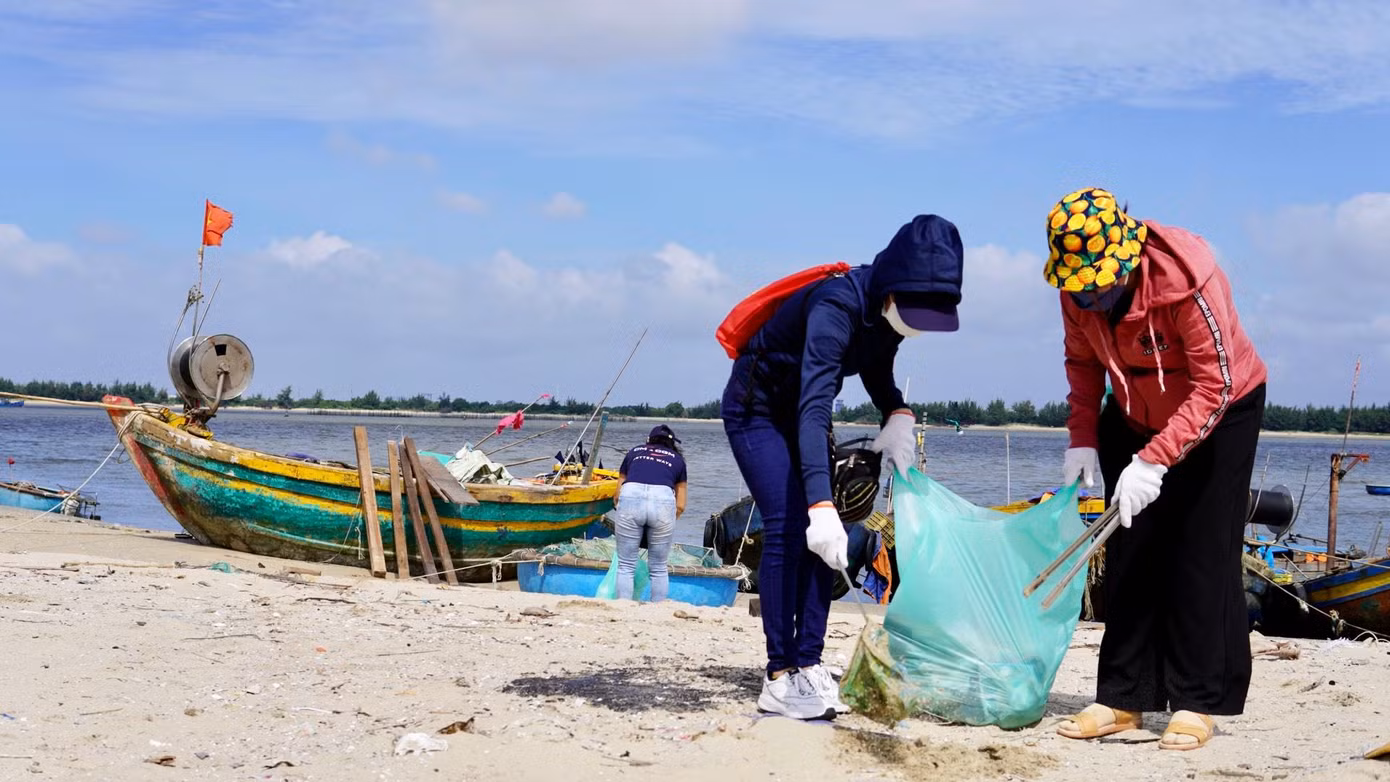 Các bạn trẻ đang nhặt rác ngoài bãi biển.