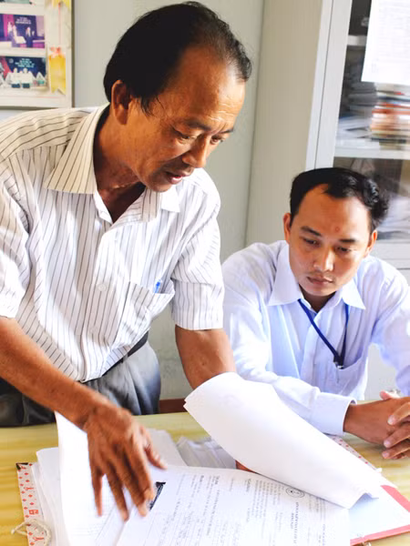 Ông Nguyễn Văn Cồn với chồng hồ sơ tồn đọng, thiếu dấu đỏ ở Hoàng Sa từ cuối 2010 tới nay. Ảnh: Nam Cường